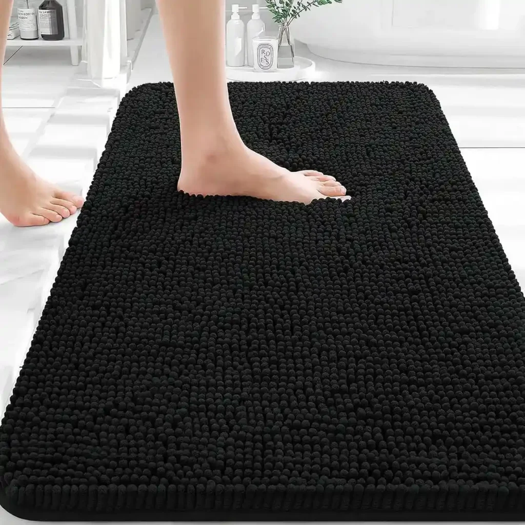 Black chenille bath mat with shaggy textured surface in modern white bathroom