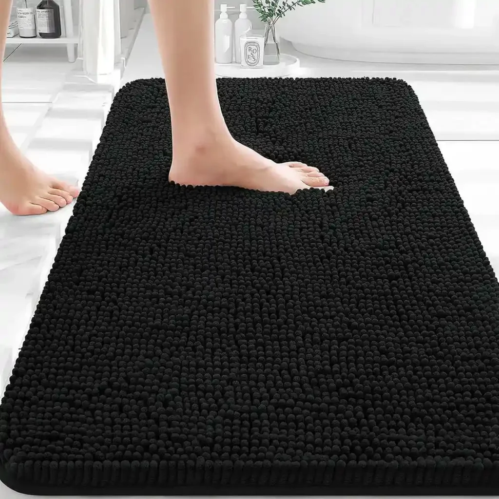 Black chenille bath mat with textured shaggy surface in modern white bathroom