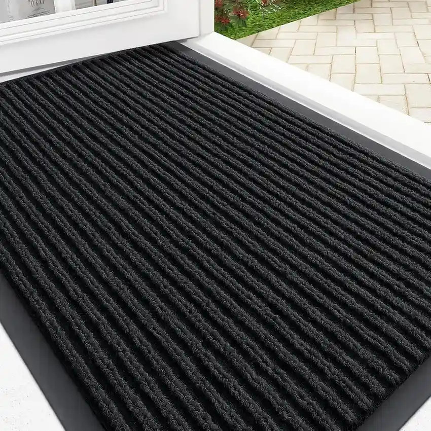 Black ribbed textured entryway mat with rubber border at front door entrance