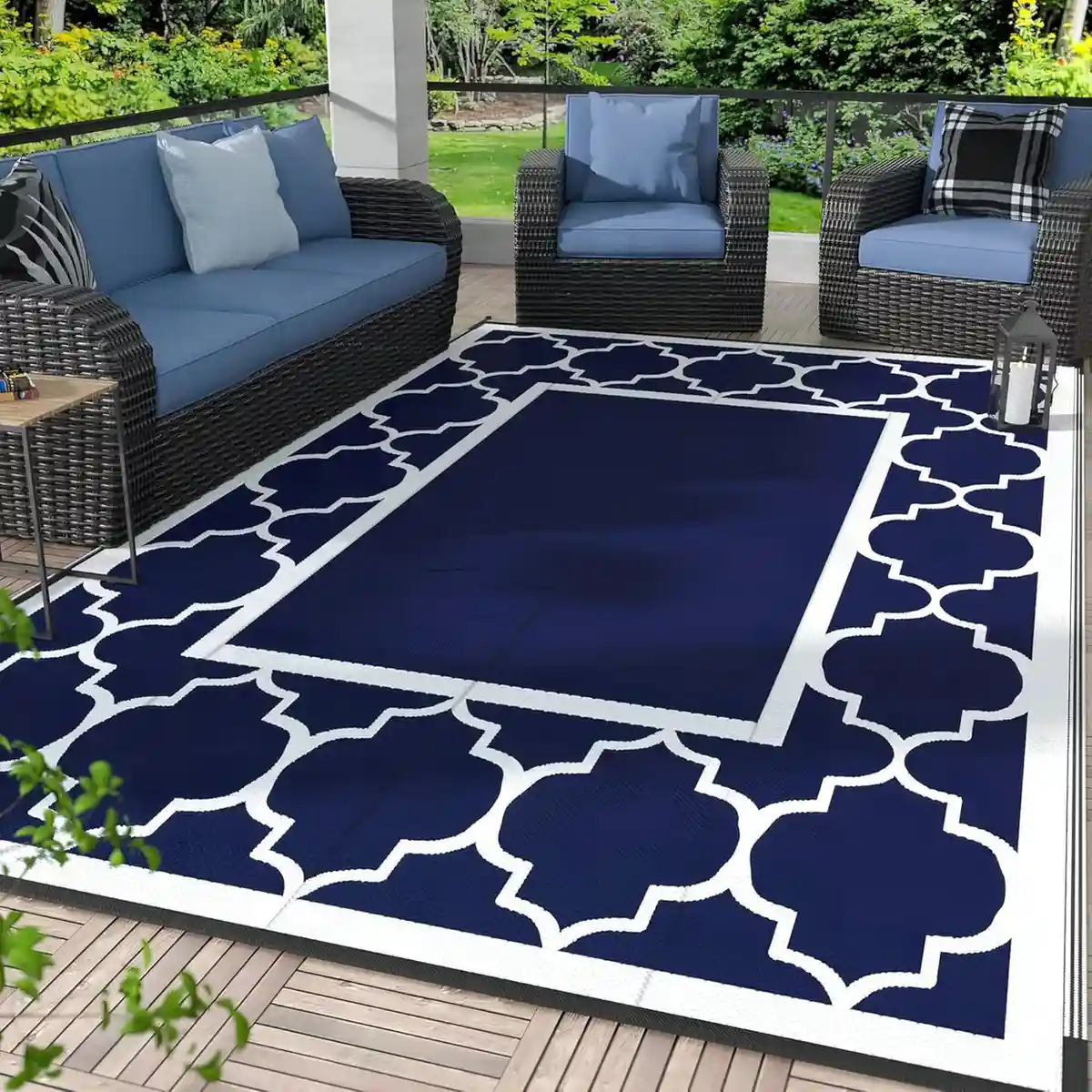 Navy blue outdoor patio rug with white geometric quatrefoil border on wooden deck