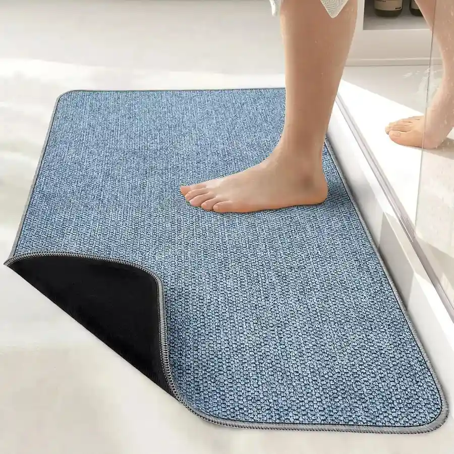 Light blue non-slip bath mat with textured surface and black backing in bathroom