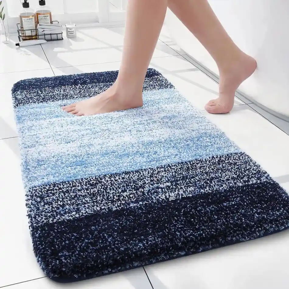 Ombre blue striped bath mat with gradient colors from navy to light blue in white bathroom