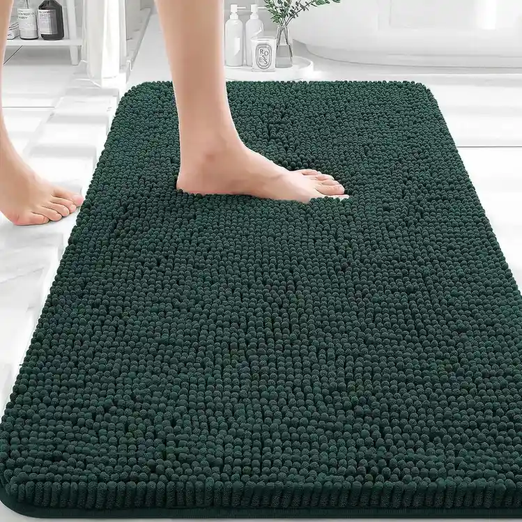 Dark forest green chenille bath mat with textured shaggy surface in white bathroom.