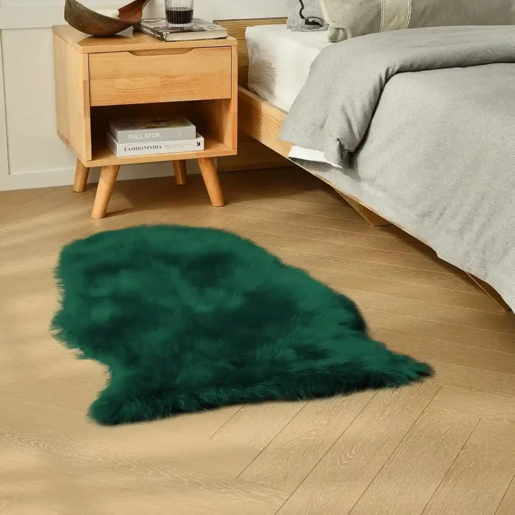 Dark emerald green faux sheepskin fur rug beside bed in modern bedroom with wooden nightstand.
