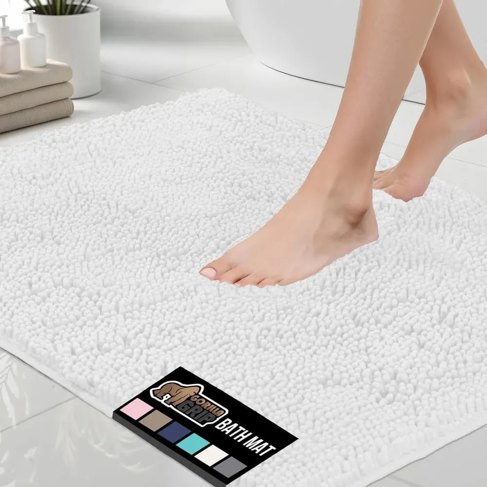 Woman stepping onto a white chenille bath mat with non-slip grip in a clean modern bathroom