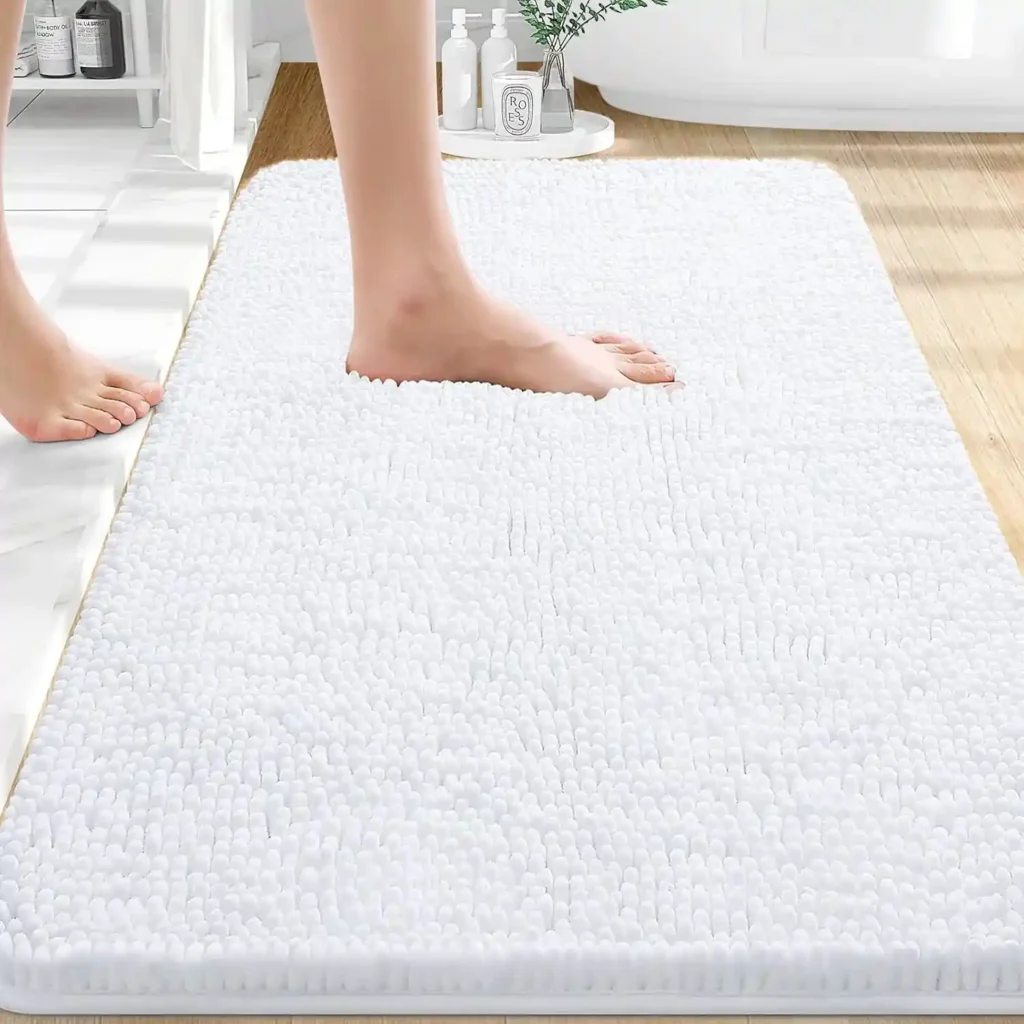 Bare feet stepping onto a thick white chenille bath mat in a modern bathroom.