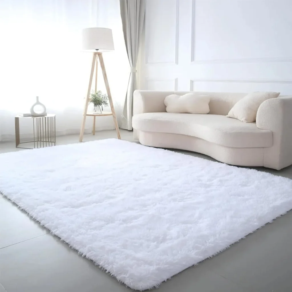 Large white fluffy shag area rug in a minimalist all-white living room with cream boucle sofa and tripod floor lamp