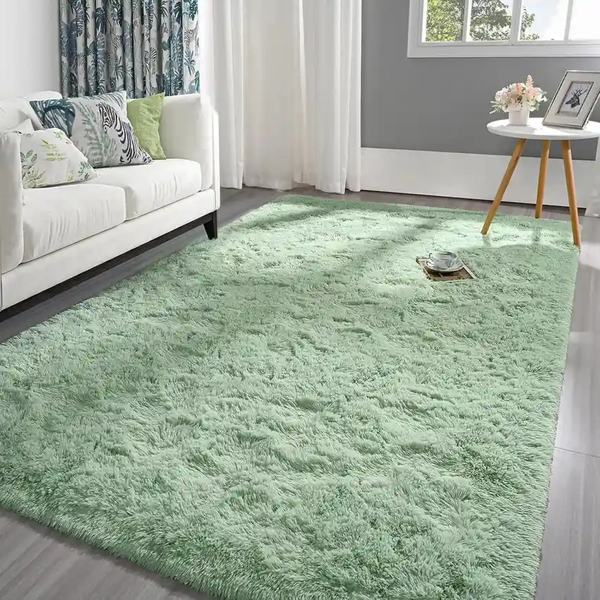 Light mint green plush shag area rug in bright living room with white sofa and tropical decor.