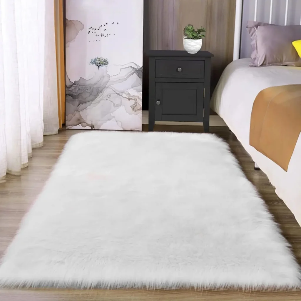 Rectangular white faux fur area rug in bedroom with plush shag texture on wooden floor.